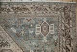 Distressed vintage Persian Kamseh rug corner, showcasing faded teal, ivory, and pictorial animal motifs.