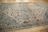 Distressed Kamseh carpet detail: faded geometric patterns in dusty teal and chocolate brown.