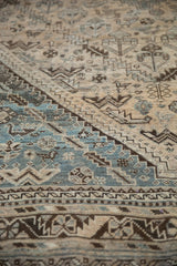 Worn texture of a vintage Kamseh rug with faded blue, cream, and brown geometric patterns.