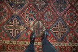 Vintage Bakhtiari carpet with red field, sapphire blue lattice, floral motifs, and visible wear.