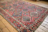 Red Bakhtiari carpet showing lattice diamond panels, garden motifs, and crab border.