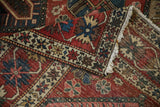 Detail of vintage Bakhtiari rug with inverted red, blue, beige lattice floral motifs and fringe.