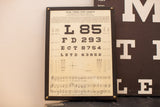 Antique 1935 solid wood eye chart plaque, near vision tests on cream, dark frame.