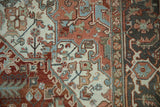 Heriz carpet detail showing serrated floral patterns in chestnut, slate blue, and ivory.