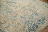 Distressed vintage Heriz carpet showing geometric blossoms in faded cream, dusty teal, and sand.