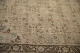Distressed vintage Bijar carpet showing muted Herati motifs and a detailed floral border in beige and chocolate brown.