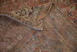Folded vintage Kamseh carpet detail: madder rust pile wear, woven foundation, and intact side selvage.