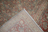 Distressed Tabriz rug corner, revealing its Herati pattern, woven foundation, machine-bound side, and fringe.