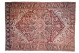 Distressed vintage Heriz rug with geometric medallion and palmette details in red, bronze, green.