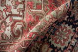 Worn, textured pile of a distressed Heriz carpet, with red, sea foam green, and beige patterns.