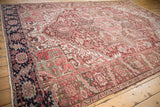 Distressed Heriz carpet detail featuring muted burgundy, beige, sea foam green geometric patterns.