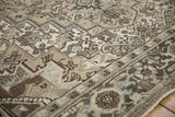 Distressed Heriz rug corner, geometric spandrels, scrolling motifs, beige, dusty teal, charcoal.