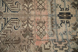 Distressed vintage Heriz carpet showing geometric floral design elements in faded blush, coffee brown, and charcoal.