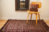 Vintage Hamadan rug with red and ivory herati design, visible under a wooden chair.
