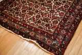 Time-softened red and ivory Herati pattern on a mid-century Persian Hamadan rug corner.