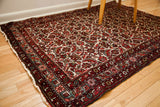 Corner detail of a vintage Persian Hamadan rug, rich red border with ivory fringe.