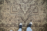 Geometric patterning and distressed texture of a vintage Mehrivan rug in beige and brown.