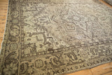 Distressed Mehrivan carpet corner displaying geometric patterns in time-softened beige and charcoal.