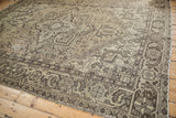 Vintage distressed Mehrivan carpet corner, showing geometric patterns and time-softened beige with charcoal tones.