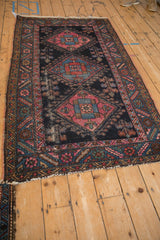 Angled view of an antique Mehriban rug, displaying visible wear and geometric medallions.