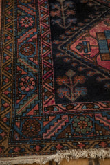 Tattered fringe, historic geometric border, and worn navy field of an antique Mehriban rug.