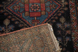 Hand-knotted back, tattered edge, and dark navy geometric floral motifs of an antique Mehriban rug.