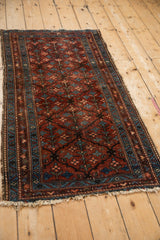 Persian Mehriban rug's worn edge, sapphire blue geometric borders, and burgundy tree-of-life motifs.