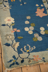 Antique Chinese Art Deco rug close-up: cobalt blue field, dusty blush lotus, eucalyptus, worn edge.