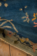 Folded antique Chinese Art Deco rug, revealing cobalt blue pile, floral motifs, and tattered edge.