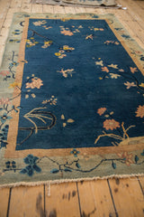 Art Deco rug corner, showing cobalt blue field, dusty blush florals, time-softened green border, and fringe.