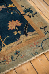 Art Deco rug's cobalt blue field, ivory border, floral motifs, and frayed wool edge.