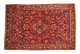 A vintage German Sarouk rug with a diamond medallion and intricate floral bouquets on a cherry red field.