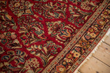 Angled view of a vintage Sarouk's intricate floral field, detailed border, and ivory fringe.