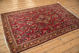 Vintage German Sarouk rug viewed at an angle, showcasing the rich cherry red and navy floral pattern.