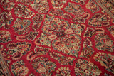 Angled view of the vintage Sarouk's covered field of intricate floral bouquets on cherry red.