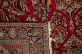 Vintage Sarouk rug corner folded to show the hand-knotted foundation, side selvage, and cherry red pile.