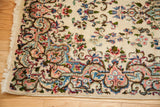 Ivory Kerman rug corner with fringe, featuring European-influenced blue and pink floral motifs.