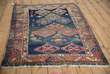 Intricate serrated medallions, human figures, and abrashed blues on an antique Caucasian rug.