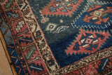 Textured geometric patterns in madder root red, navy blue, and ivory on antique Caucasian rug.