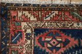 Antique Caucasian rug corner, showing serrated red, navy blue geometric motifs and fringe.