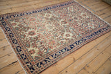 Full angled view of an antique Malayer rug, highlighting its worn ivory field and intricate floral pattern.