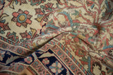 A folded antique Malayer rug showing its textured low pile, ivory floral field, and dark navy border.