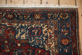 Corner detail of an antique Malayer rug with a scrolling vine arabesque spandrel and even wear.