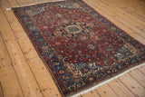 An antique Persian Malayer rug shown from a side angle, displaying its rich palette and medallion design.