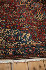 Corner detail of an antique Malayer rug, with a scrolling vine border and low, even pile.
