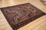 Angled perspective of an antique Malayer rug with a ruby red and sapphire blue Herati pattern.