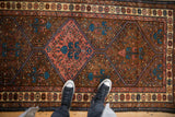 Close-up on the low pile and geometric tree-of-life medallion of a vintage Kurdish rug.