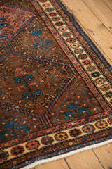 Angled view of a Kurdish rug corner, showing the pomegranate top-view border and low pile.