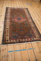 Angled perspective of a vintage Kurdish Hamadan rug highlighting its triple medallion and pomegranate border.