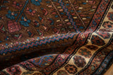 A fold in the vintage Kurdish Hamadan rug shows its hand-knotted pile and rich wool texture.